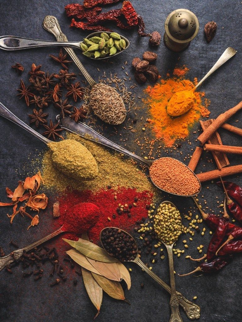 Whole spices and seasonings arranged on a dark slate